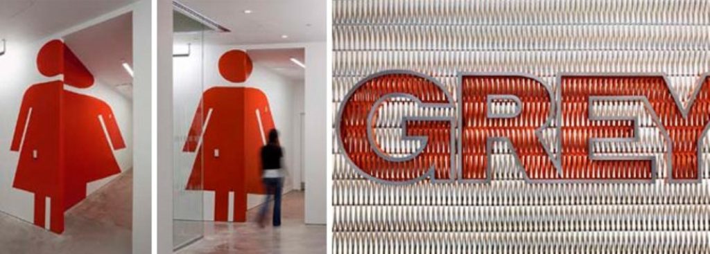 GREY GROUP - עיצוב סביבתי לחברת תקשורת שיווקית: השלט של לוגו החברה ועיצוב הפנים של המשרדים עשויים מאותם חומרים. שימוש באייקון השירותים בכניסה ובמסדרון.